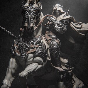 Può includere: Scultura dettagliata di un cavaliere con armatura ornata a cavallo di un cavallo bianco. Il cavaliere indossa un elmo e un mantello, tenendo una lancia. L'armatura del cavallo e l'equipaggiamento del cavaliere presentano disegni intricati, con un'estetica scura e drammatica.
