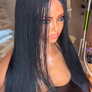 May include: A black micro braid wig with a natural-looking hairline. The wig features long, sleek braids that cascade down the shoulders. The braids are neatly styled, offering a polished and elegant appearance. This wig is a stylish hair accessory.