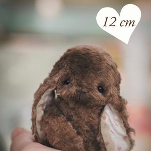 May include: A brown plush bunny, approximately 4.7 inches (12 cm) tall, with floppy ears and a sweet expression. The ears have a pink heart pattern on the inside. The text "PDF PATTERN" is at the bottom.