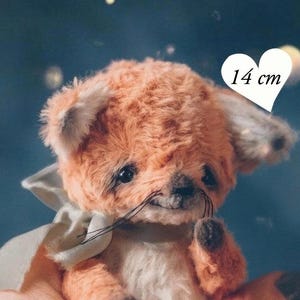 Peut inclure: Une peluche renard faite à la main, de couleur orange et crème, mesurant 14 cm de haut. Le renard en peluche a une expression douce, des moustaches et un nœud crème. Le texte "PDF pattern" est visible.