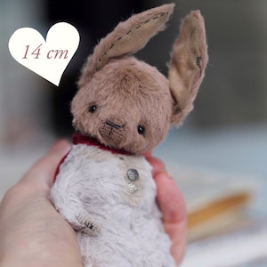 May include: A handmade plush bunny, approximately 5.5 inches tall, with a brown head and long ears. The bunny wears a red collar and a decorative button. The text "PDF PATTERN" is visible.