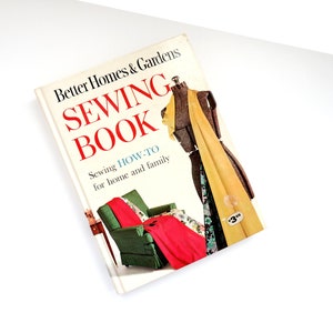 Puede incluir: Un libro de costura vintage de Better Homes & Gardens con un maniquí de costura amarillo y marrón, un sillón verde con una manta roja y el texto "Coser: Cómo hacerlo para el hogar y la familia".
