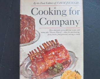 May include: A vintage cookbook titled "Cooking for Company" by the Food Editors of Farm Journal. The cover features images of cooked food, including a roast and a cake. The book promises over 900 recipes and ideas for entertaining.