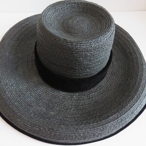 May include: A wide-brimmed black straw hat with a black velvet band.
