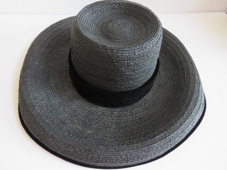 May include: A wide-brimmed black straw hat with a black velvet band.