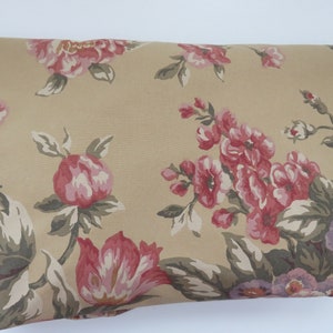 Pode incluir: Tecido bege com um padrão floral com flores rosa e roxas. O tecido tem uma estética vintage.