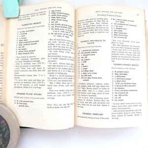 May include: An open cookbook page featuring recipes for Barbecued Brisket, Swedish Flank Steaks, Venison Meatballs in Sauce, and Venison Teriyaki. The text is printed in black ink on off-white paper with visible page numbers and column headers.
