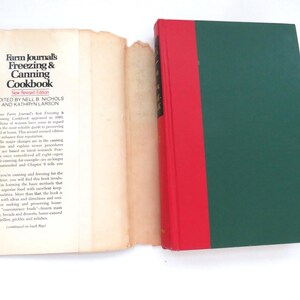 May include: A hardcover book titled Farm Journal's Freezing & Canning Cookbook with a dark green cover and a red spine. The book is displayed with its detached, cream-colored paper dust jacket laid flat to the left, showing printed text.