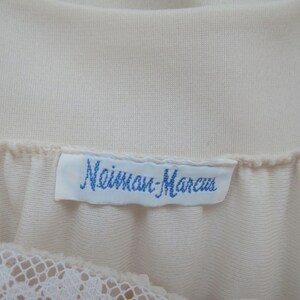 May include: A white label with blue text that reads "Mainman-Marcus" attached to a white garment.