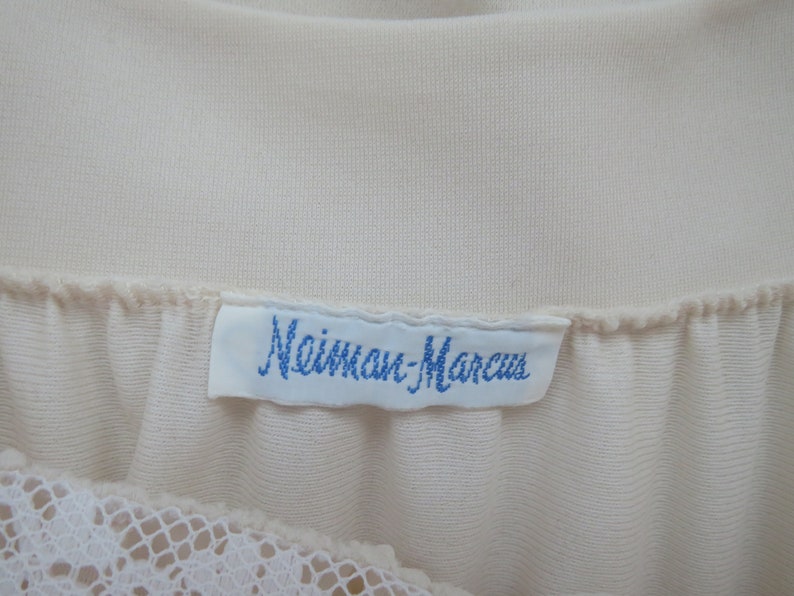 May include: A white label with blue text that reads "Mainman-Marcus" attached to a white garment.