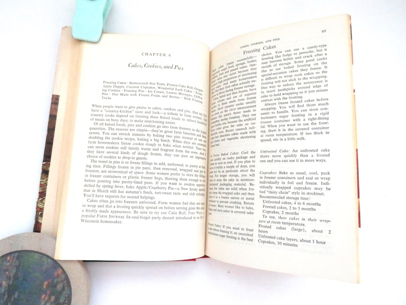 May include: An open vintage cookbook page titled Chapter 6: Cakes, Cookies, and Pies, featuring printed black text on off-white paper. The content provides instructions for freezing cakes, cookies, and pies, with a light blue clip at the top edge.