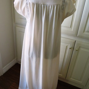 May include: A white, long, sleeveless nightgown with lace trim on the neckline and sleeves. The gown is made of a soft, silky fabric.
