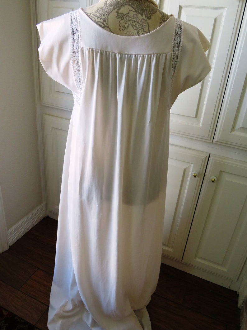 May include: A white, long, sleeveless nightgown with lace trim on the neckline and sleeves. The gown is made of a soft, silky fabric.