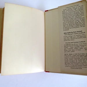 Puede incluir: Un libro abierto con una cubierta blanca y una encuadernaci&oacute;n roja. El libro se titula "Farm Journal's Country Cookbook". La contraportada presenta texto sobre otros libros de Farm Journal, incluyendo "Farm Journal's Country Cookbook", "Freezing and Canning Cookbook" y "Field Food Editor for Farm Journal".
