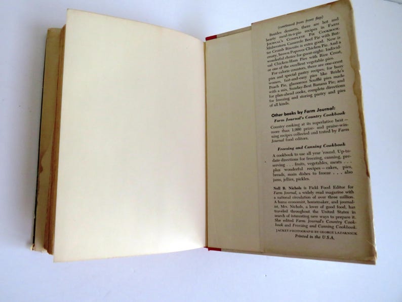 Puede incluir: Un libro abierto con una cubierta blanca y una encuadernaci&oacute;n roja. El libro se titula "Farm Journal's Country Cookbook". La contraportada presenta texto sobre otros libros de Farm Journal, incluyendo "Farm Journal's Country Cookbook", "Freezing and Canning Cookbook" y "Field Food Editor for Farm Journal".