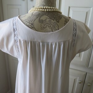 May include: A white nightgown with lace trim on the sleeves. The nightgown has a scoop neck and a gathered bodice.