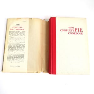 Puede incluir: Un libro de cocina vintage titulado "Farm Journal's Complete Pie Cookbook" con una encuadernaci&oacute;n roja. El libro est&aacute; abierto en la contraportada, que tiene texto que describe el contenido del libro.