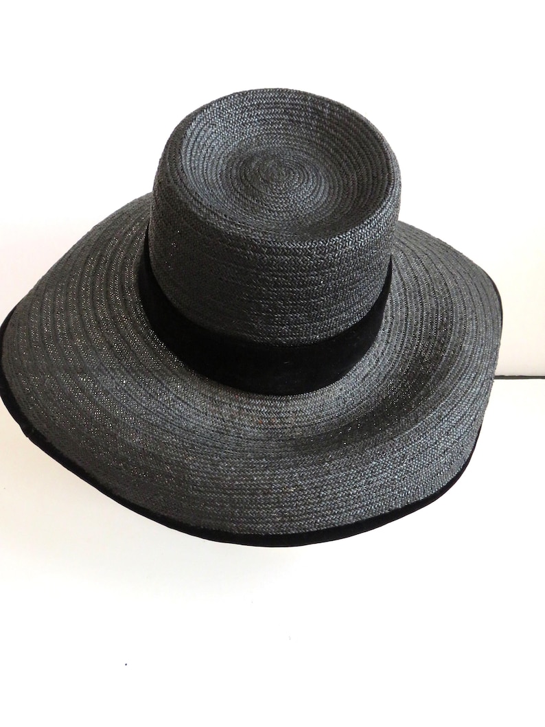 May include: A black wide-brimmed straw hat with a black velvet band.