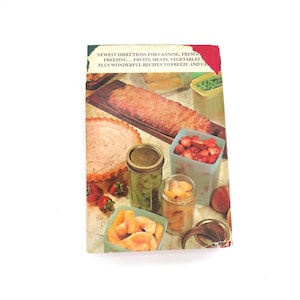 May include: A vintage cookbook with a rectangular cover featuring a color photograph of various preserved foods, including a loaf, a pie, and glass jars filled with fruits and vegetables. The text reads: NEWEST DIRECTIONS FOR CANNING, PRESERVING, FREEZING... FRUITS, MEATS, VEGETABLES, PLUS WONDERFUL RECIPES TO FREEZE AND CAN.