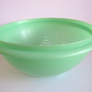 May include: A light green plastic colander with a removable lid. The colander has a round shape and a smooth surface. The lid has a pattern of small holes.