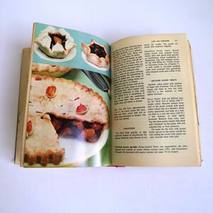 Puede incluir: Libro de cocina abierto con una receta para pasteles de masa sobrante. El libro tiene una imagen de un pastel con una corteza y un relleno de fruta. El texto en la p&aacute;gina dice "Pasteles de masa sobrante".
