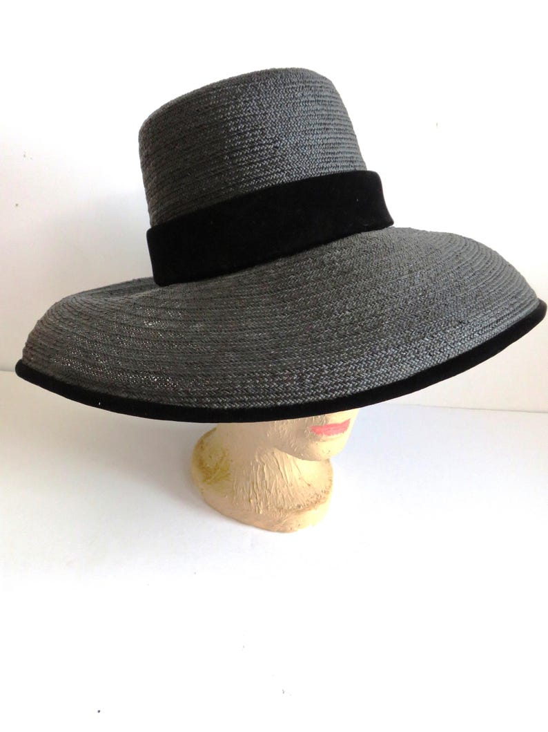 May include: A wide-brimmed black straw hat with a black velvet band.