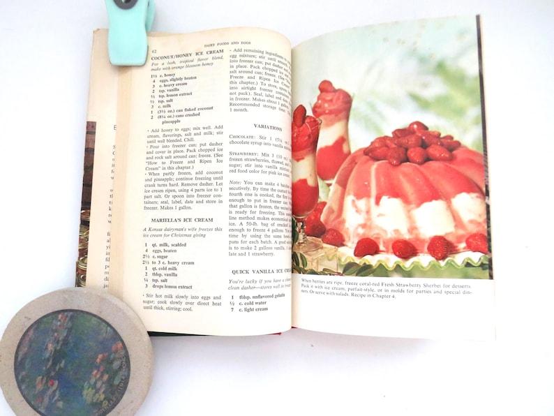 May include: An open vintage cookbook page featuring a recipe for Coconut Honey Ice Cream and Mariella's Ice Cream. The right page displays a color photograph of a molded strawberry sherbet dessert topped with fresh strawberries and two tall glasses.
