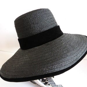 May include: A wide-brimmed black straw hat with a black velvet band around the crown.