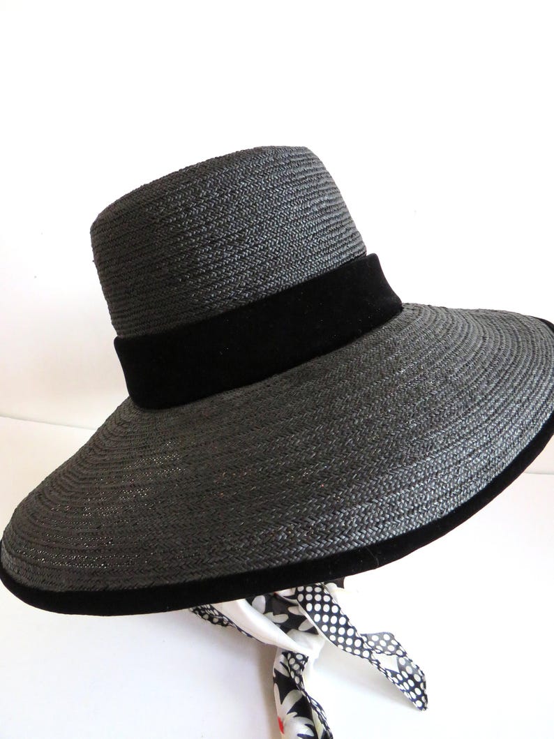 May include: A wide-brimmed black straw hat with a black velvet band around the crown.
