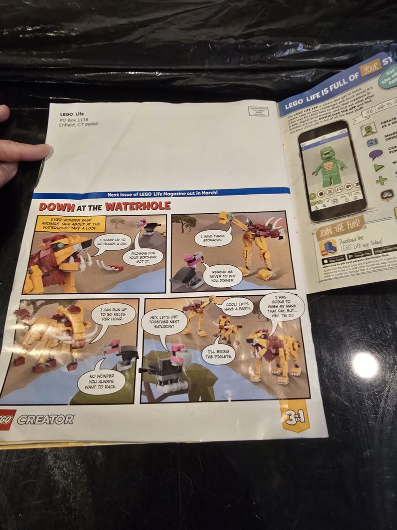 May include: A LEGO Creator 3-in-1 magazine page featuring a comic strip titled Down at the Waterhole with various animal figures. The page includes text, a smartphone graphic showing a green character, and the LEGO Life logo in the top corner.