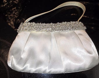 Pochette bianca in raso con bordo gioiello e manico, scritta NYT Lites Top 8", stile vintage anni '80.