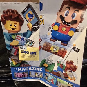 May include: A promotional LEGO Life magazine featuring a LEGO minifigure holding a smartphone, a LEGO Mario figure jumping above a brick-built question block, and various smaller images showcasing new models, comic action, activities, and cute animals.