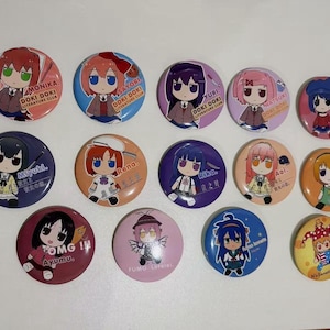 May include: A collection of fourteen circular pin-back buttons featuring various anime-style chibi characters. Each button displays a unique character illustration with their name and associated text, including Doki Doki Literature Club, Mita, Miyuki, Rena, Rika, Aoi, Satoko, Ayumu, Fumo Lorelei, Fumo Konata, and It's Lunatic Time.