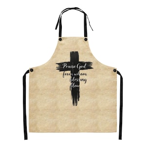 May include: Beige apron with black cross and text. The apron has a black cross design and the words "Praise God from whom blessing flow" in black script. It has black ties and a neck strap.