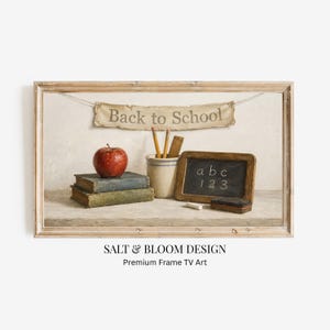 Pode incluir: Uma impressão de arte emoldurada apresentando uma faixa com o texto Back to School, uma maçã vermelha sobre dois livros antigos empilhados, um pote de cerâmica com dois lápis, uma pequena lousa de madeira com abc 123 e um apagador de giz.