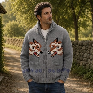 May include: A grey knit zip-up cardigan featuring a shawl collar and two front pockets. The garment displays a repeating fox head graphic on the chest and a row of purple paw print patterns along the bottom hem, worn over a white t-shirt and blue jeans.