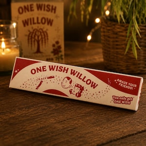 May include: A rectangular cardboard box labeled ONE WISH WILLOW in red text on a cream background. The box features illustrations of two faces, a cracking stick, and stars, with the text AMAZE YOUR FRIENDS and You only, get ONE WISH printed on it.
