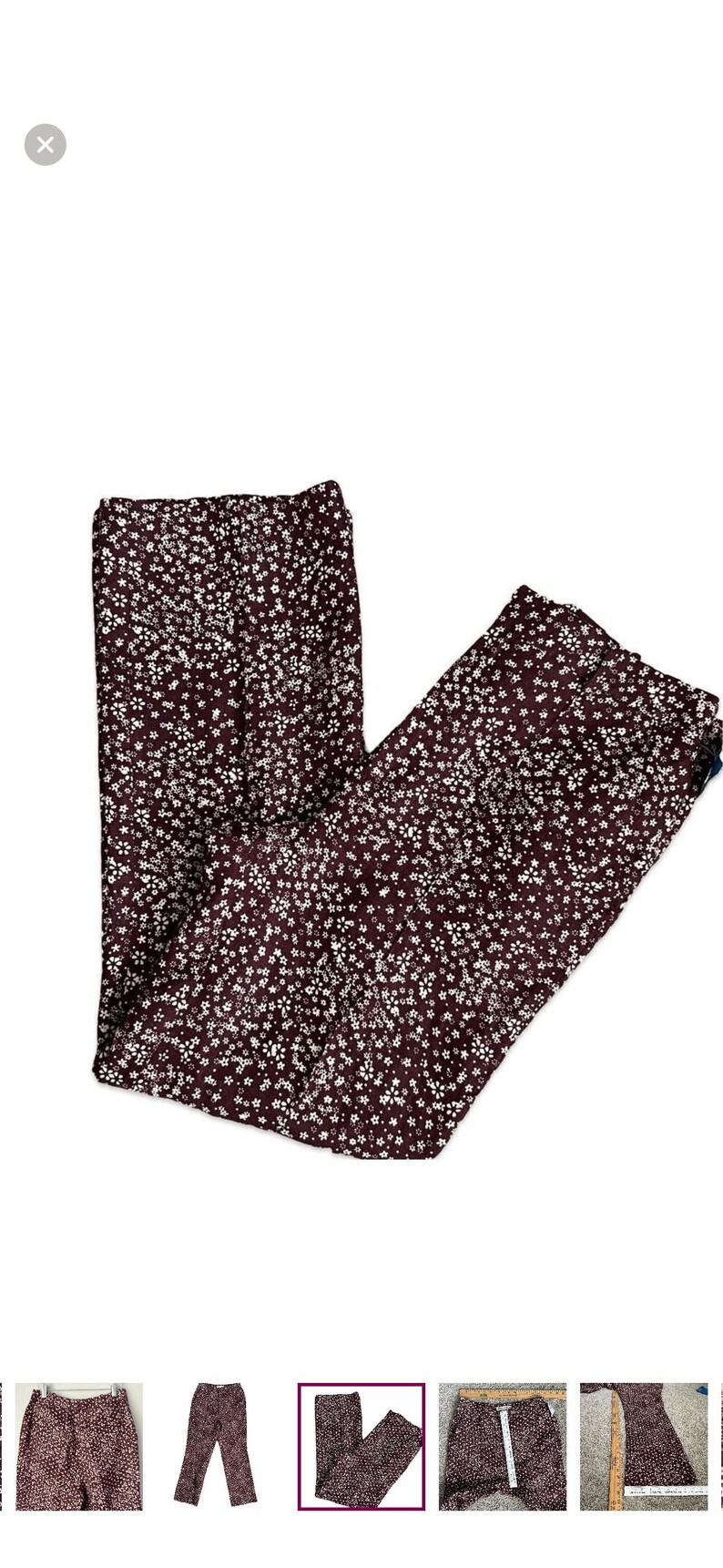 May include: Burgundy-colored pants with a white floral pattern. The pants are made of a lightweight fabric and have a straight leg cut. The floral print is evenly distributed across the fabric.
