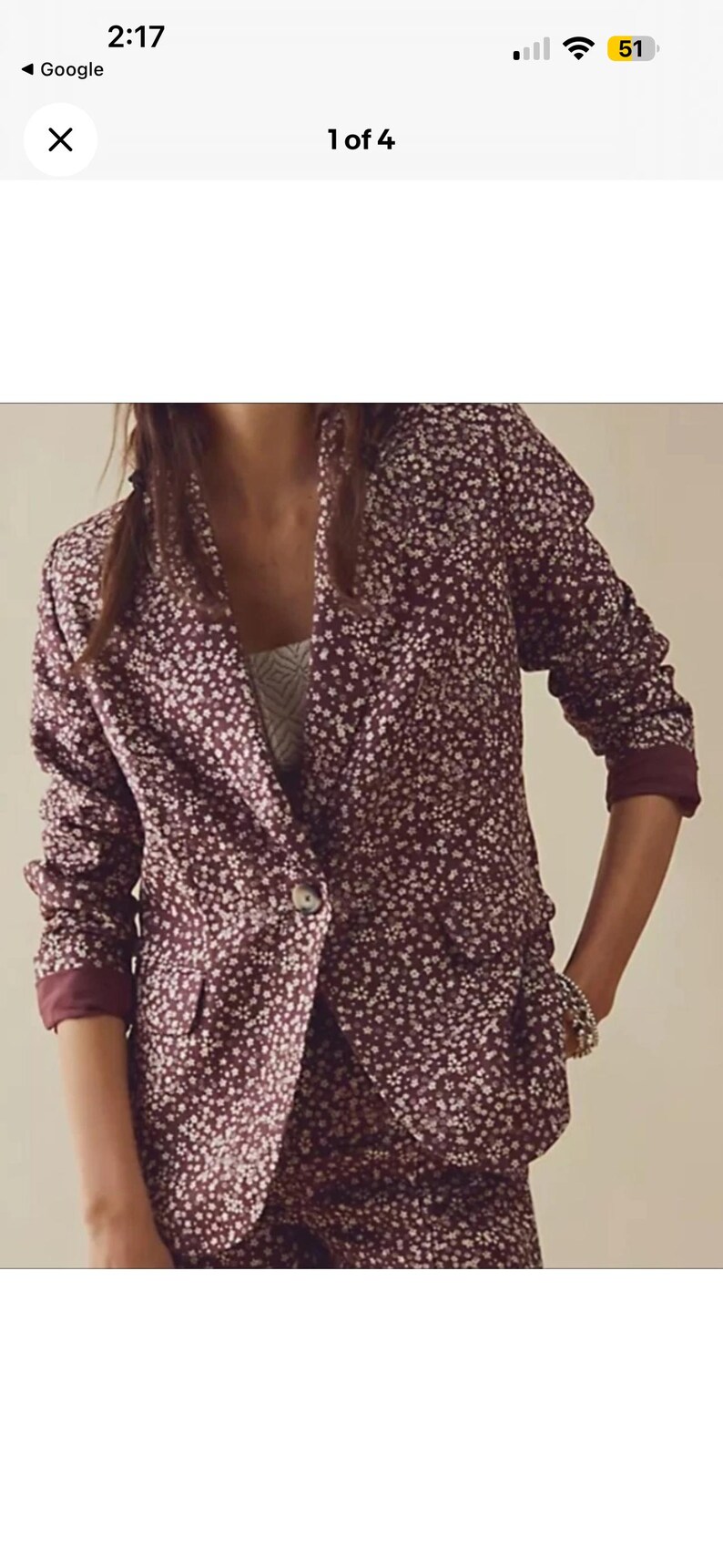 May include: A burgundy blazer and matching bottoms set with a white floral pattern. The blazer has a single button closure and the sleeves are cuffed. The outfit is a stylish ensemble for a variety of occasions.