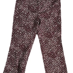 May include: Burgundy-colored pants with a white floral pattern. The pants have a high waist and a flared leg. The fabric appears to be a lightweight material, suitable for warmer weather. The pants are displayed on a white background.