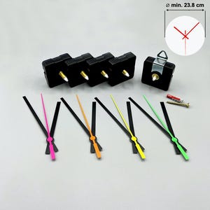 Könnte beinhalten: Uhrwerksteile, darunter schwarze Uhrwerke, farbige Zeiger in Pink, Orange, Gelb und Grün sowie eine Skizze mit einem Mindestdurchmesser von 23,8 cm. Die Zeiger sind schwarz mit farbigen Spitzen.