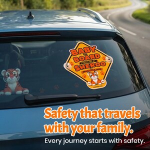 May include: A diamond-shaped yellow car sign with orange text reading BABY ON BOARD PROTECTED BY SHEROO THE BRAVE LITTLE TIGER, featuring a tiger illustration and paw prints. The sign is attached to a car window with two clear suction cups.