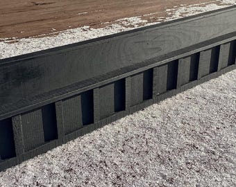 Puede incluir: Dos estructuras rectangulares largas de madera negra con una superficie superior lisa y una serie de listones verticales en el lado frontal. Cada pieza presenta extremos en ángulo y un acabado oscuro uniforme con textura de veta visible.