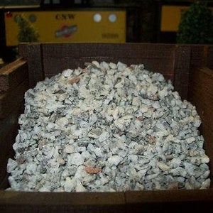 May include: A close-up of a wooden box filled with gray gravel. The gravel is a mix of small and large stones.