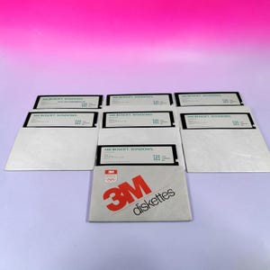May include: A collection of black 3.5-inch floppy disks labeled Microsoft Windows, each housed in a white paper sleeve. One sleeve features a red 3M logo with Olympic rings and the text 3M diskettes. The disks are arranged in a grid formation.
