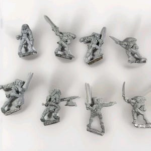 May include: A collection of eight unpainted miniature fantasy figures, each depicting a warrior in dynamic poses. The figures are made of a silver-colored metal and are designed for tabletop gaming or collecting. Some figures hold swords or axes.