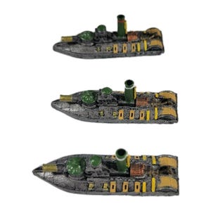 May include: Three miniature toy boats with a dark gray hull, green turrets, and yellow and brown accents. Each boat has a tall green smokestack. The boats are arranged vertically against a white background.