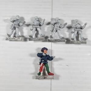 May include: Miniature figurines of medieval figures. Four are silver-colored, and one is painted with a purple hat, blue jacket, and red and green pants. The figures are standing on small, rectangular bases.