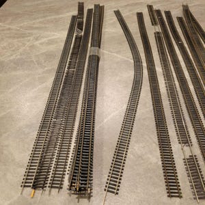 Könnte beinhalten: Eine weiße Keramik-Tasse mit schwarzem Henkel und dem Text "But First, Coffee" in fetter, schwarzer Schrift. Die Tasse steht vor einem verschwommenen Hintergrund. Die Tasse ist etwa 10 cm hoch.