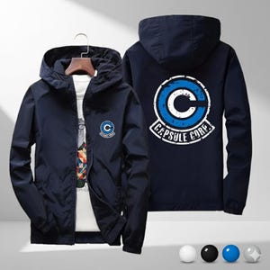 以下が含まれることがあります： 白と青のカプセルコーポレーションのロゴが背面に、小さなロゴが前面に付いた、ネイビーブルーのフード付きジャケット。 ジャケットはフルジッパーとフード付きです。 ジャケットは前面と背面から表示されています。